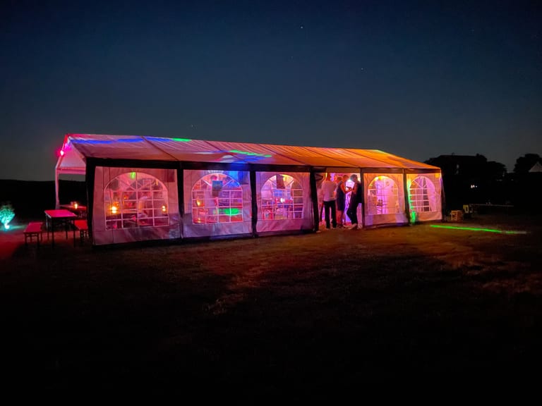 Neonbeleuchtetes D-CRIME Festzelt unter dem Nachthimmel
